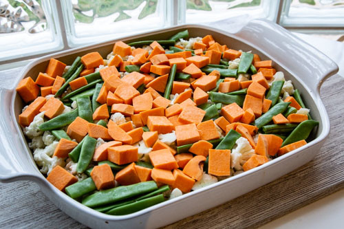 Pampered Chef flacher Bäker Süßkartoffel-Blumenkohl-Auflauf mit Zuckerschoten vor dem Backen